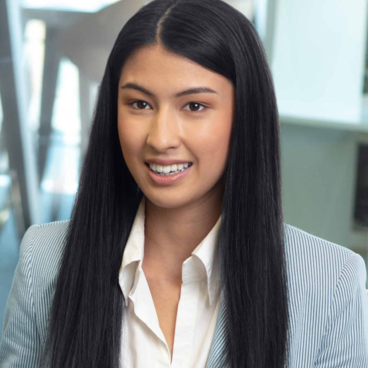 woman with long black hair and blue pinstripe blazer smiling