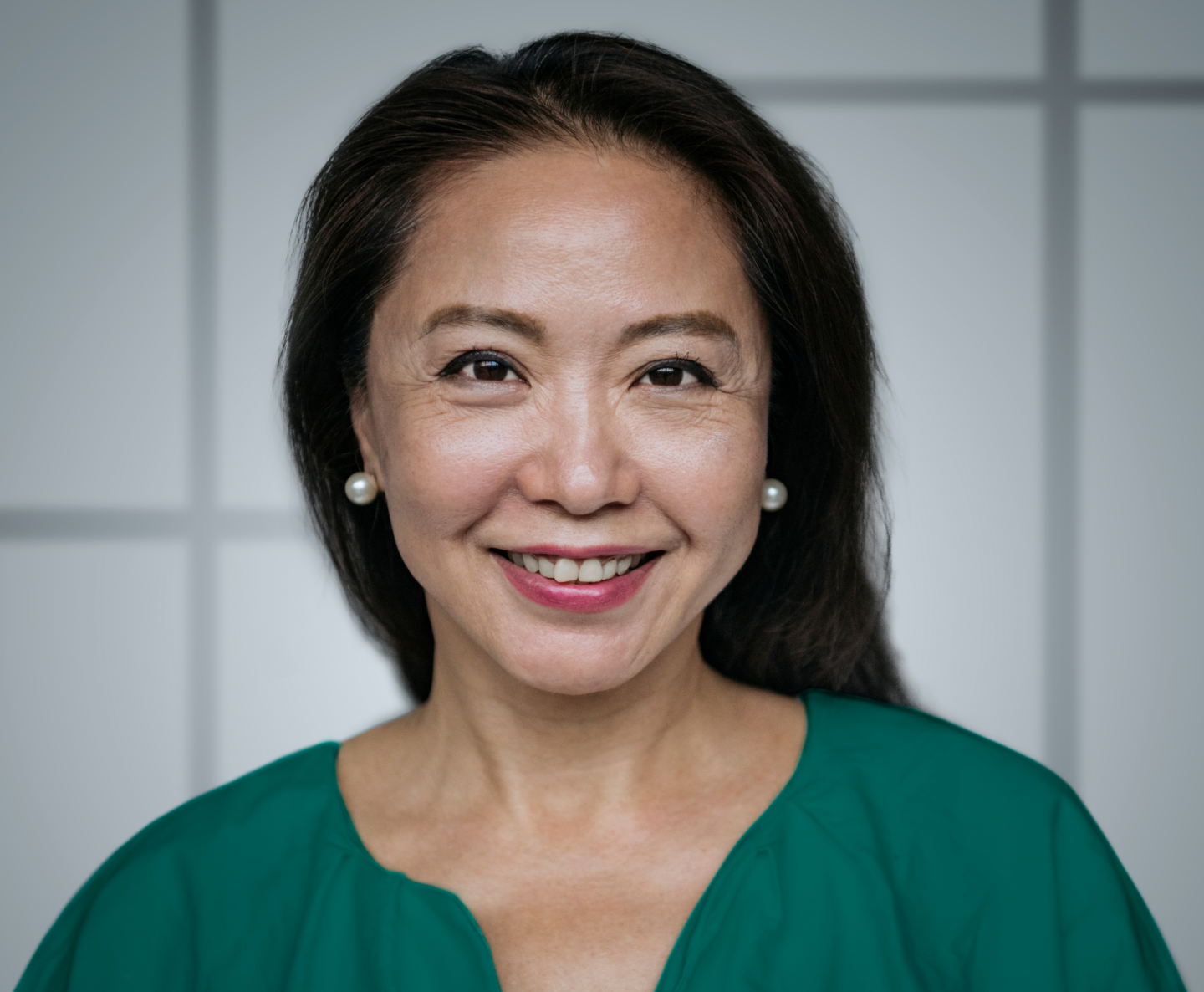 woman with black hair and pearl earrings smiling