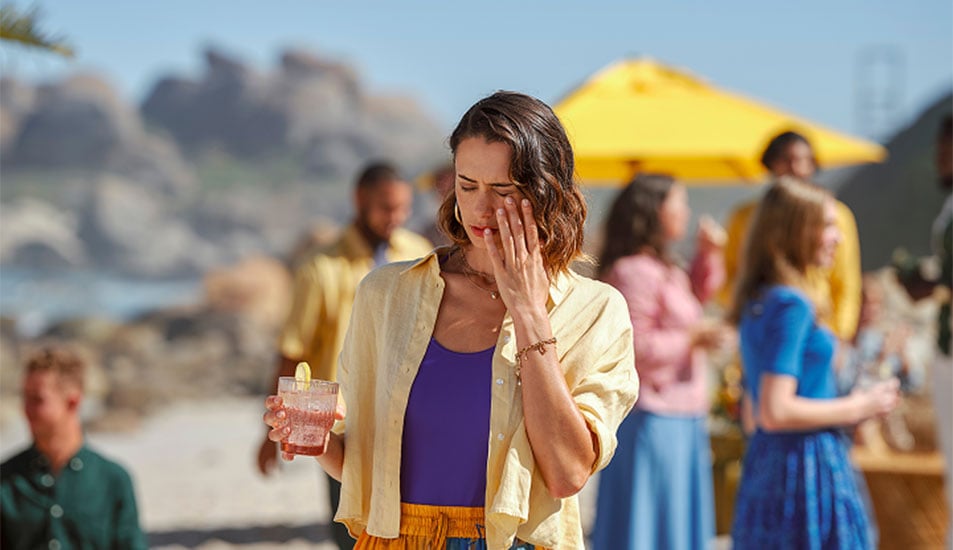 Woman on the beach with her hand over her left eye