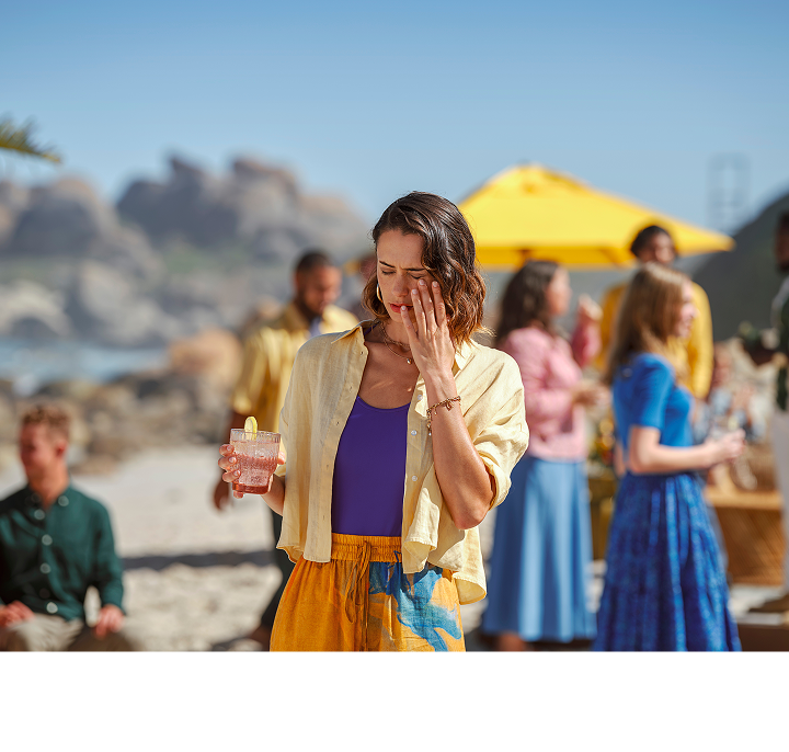 Woman on the beach with her hand over her left eye