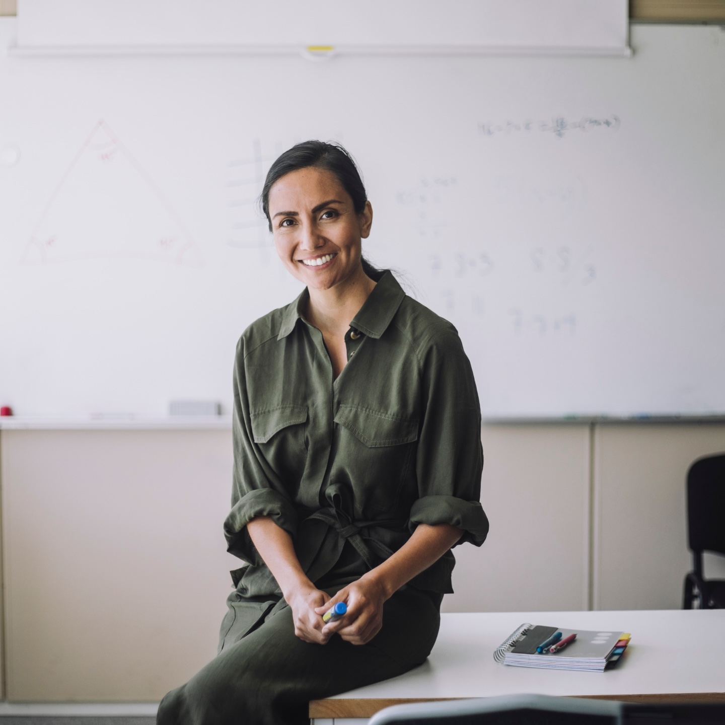 Smiling woman in a green shirt with a classroom in the background