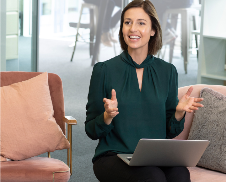 Kvinde med kort brunt hår taler på kontoret med bærbar computer