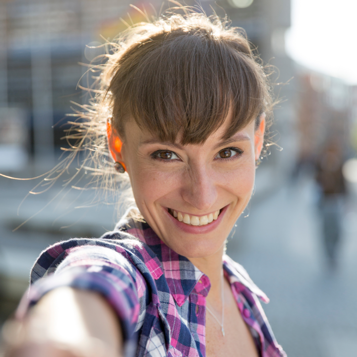 smilende kvinde iført ternet bluse, mens hun tager en selfie