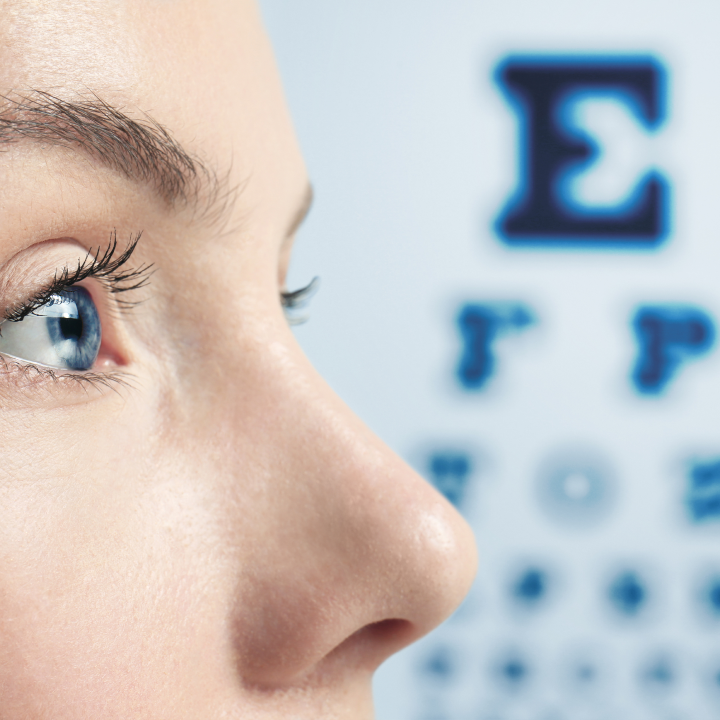 paciente con los ojos completamente abiertos leyendo una tabla para examen ocular