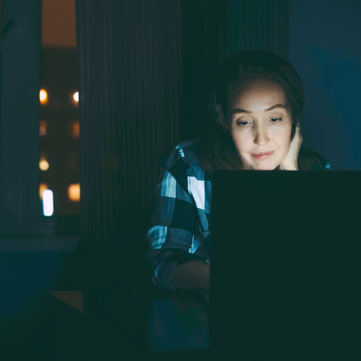 nainen, joka katsoo tietokoneen näyttöä illalla, kokee digitaalista silmien väsymistä