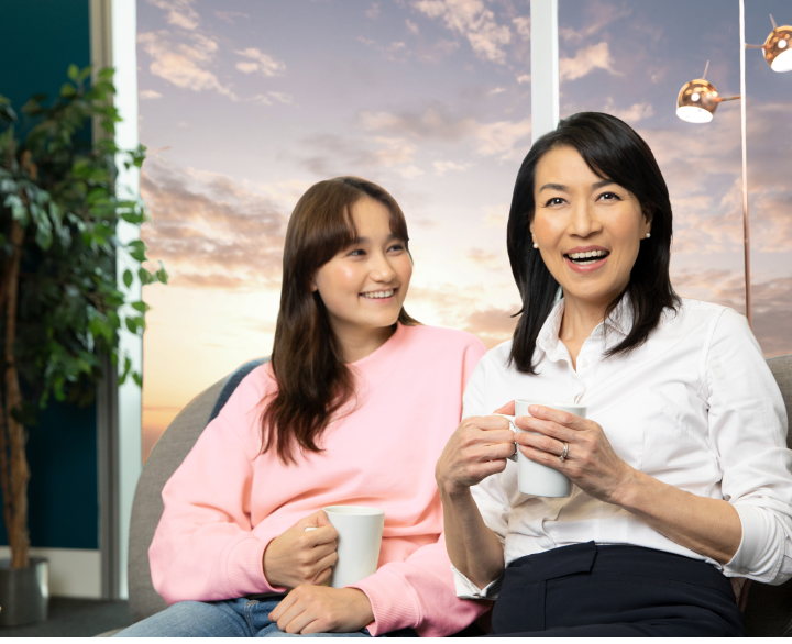 Woman and young girl laughing while holding mugs
