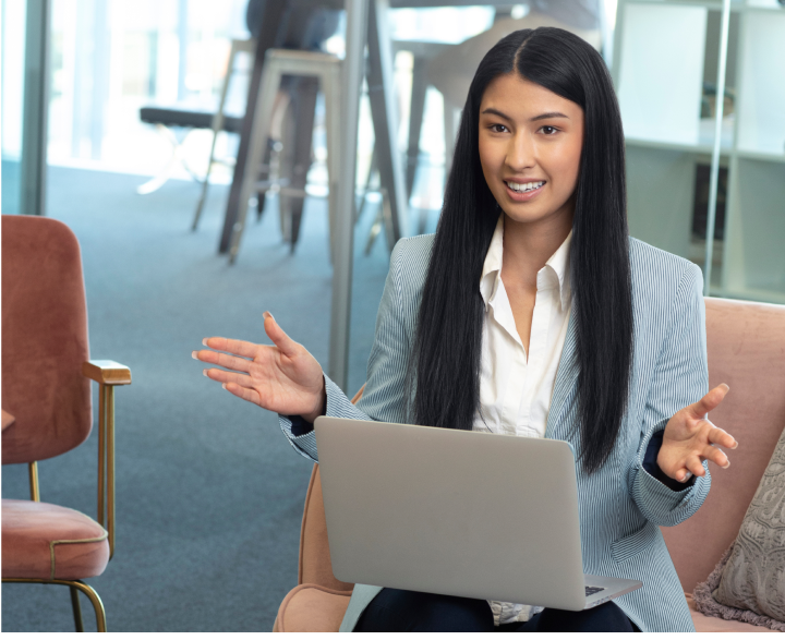 Woman with long brown hair conversing in office with laptop