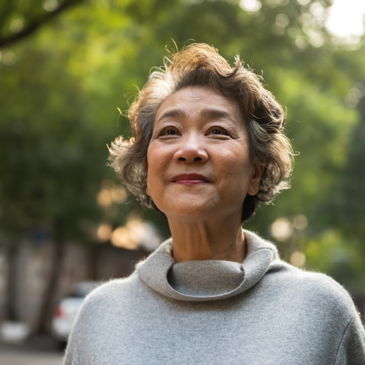 Ederly woman with short hair smiling while looking up into the distance