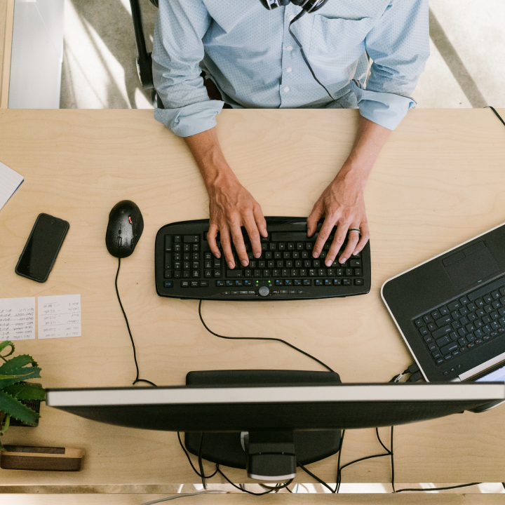 Man sitting at desk in office working typing on keyboard