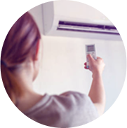 Woman operating indoor air conditioner with remote