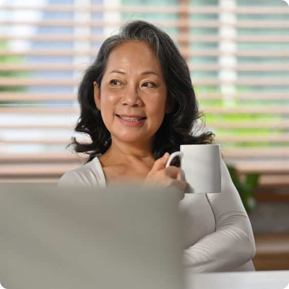 Elderly woman with cup in hand at laptop