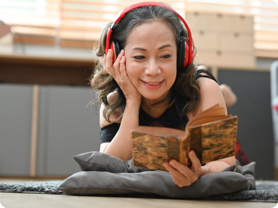 Elderly woman with headphones reading a book